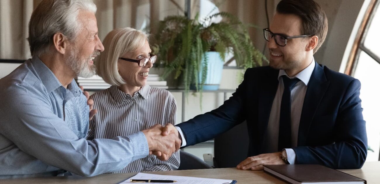 property solicitor shaking hands with elderly couple
