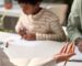 solicitor talking to parent, with child drawing in background