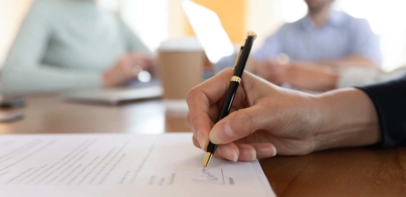 man signing contract with two other people watching