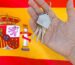 Hand holding house keys with a keyring shaped like a home, set against the Spanish flag.